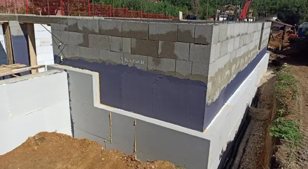 Izolacja fundamentów w starym domu w trakcie budowy. Ściany z bloczków betonowych, izolacja przeciwwilgociowa i termiczna.