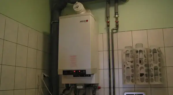 Kocioł gazowy gotowy na sezon grzewczy. W pomieszczeniu z kafelkami widać też termostat i uchwyty na papier toaletowy.
