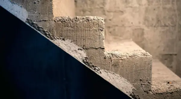 Surowe schody betonowe, idealne do rozważenia, jak tanio wykończyć schody betonowe. Widoczne nierówności i siatka zbrojeniowa.