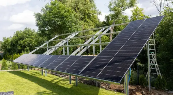 Montaż paneli fotowoltaicznych na stelażu. Instalacja PV w ogrodzie, gotowa do produkcji czystej energii.