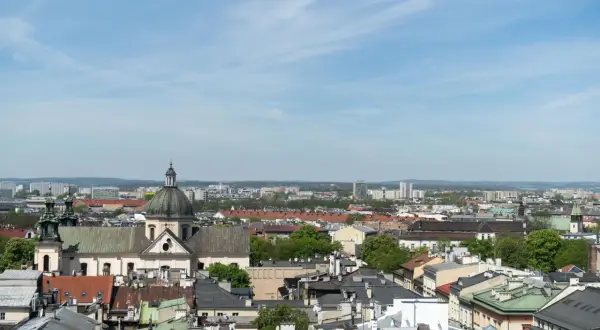 Widok na krakowskie dachy i kościół z kopułą. W tle nowoczesne budynki, które mogą wpływać na ceny mieszkań Kraków.