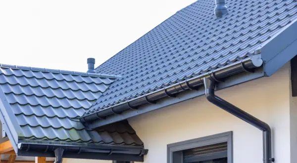 Szary dach z dachówki ceramicznej, rynny i komin. Sprawdź, jaka jest dachówka ceramiczna cena za m2 dla Twojego domu.