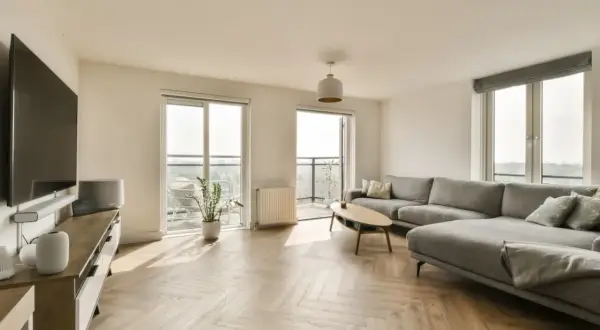 Nowoczesny salon z szarym narożnikiem i drewnianą podłogą. Idealne miejsce do relaksu, gdy rozważasz ceny mieszkań w Lublinie.