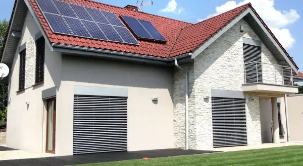 Nowoczesny dom z panelami solarnymi na dachu. Elegancka elewacja i zadbany ogród.