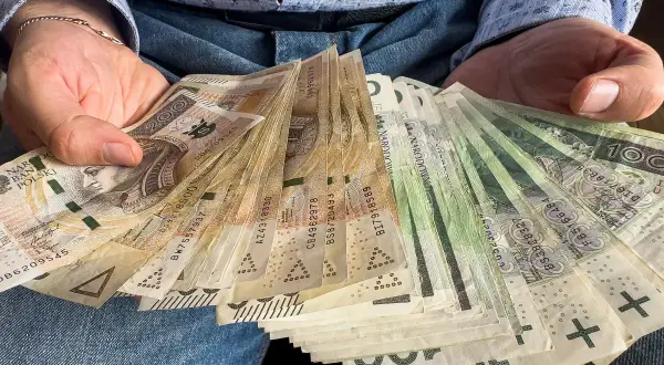 Ręce trzymające plik banknotów. To może być darowizna 200 tysięcy od rodziców, wsparcie finansowe.