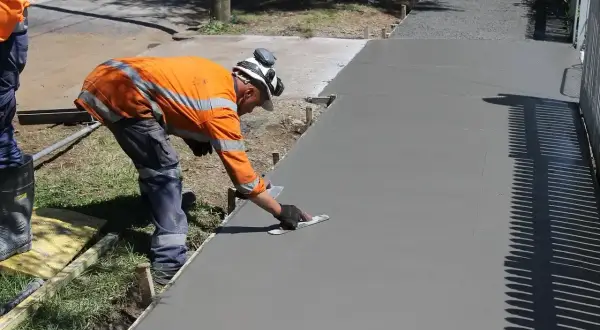 Robotnik wygładza świeży beton. Zastanawiasz się, ile kosztuje kubik betonu na podjazd?