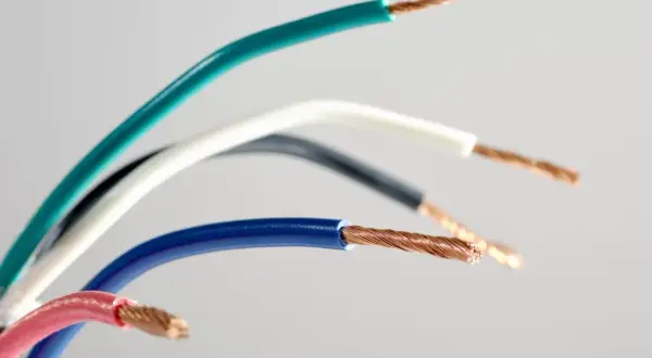 Pięć przewodów elektrycznych w różnych kolorach: zielonym, białym, czarnym, niebieskim i różowym, odsłaniających miedziane żyły. Różnorodne kolory faz.