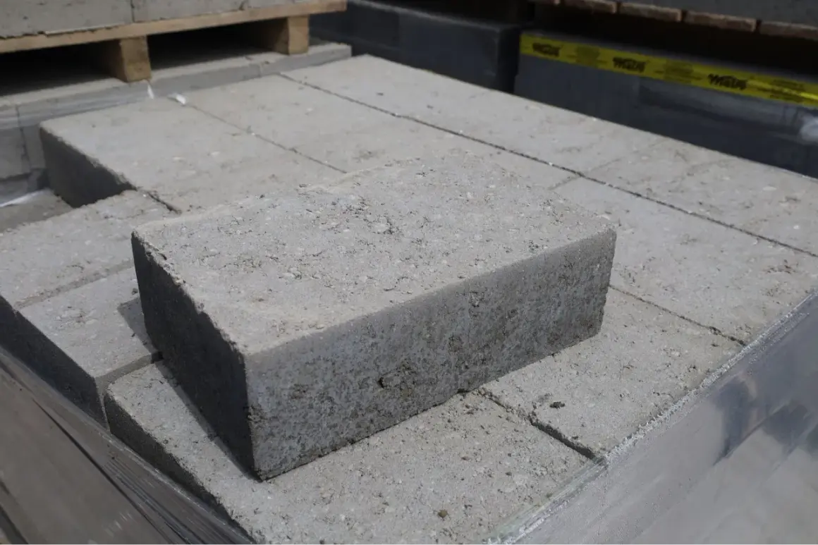 Stos szarych bloczków betonowych fundamentowych, gotowych do budowy solidnych podstaw.
