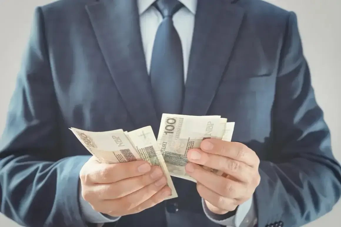 Mężczyzna w garniturze liczy banknoty 100 zł. Czy to jego zarobki jako członka rady osiedla?