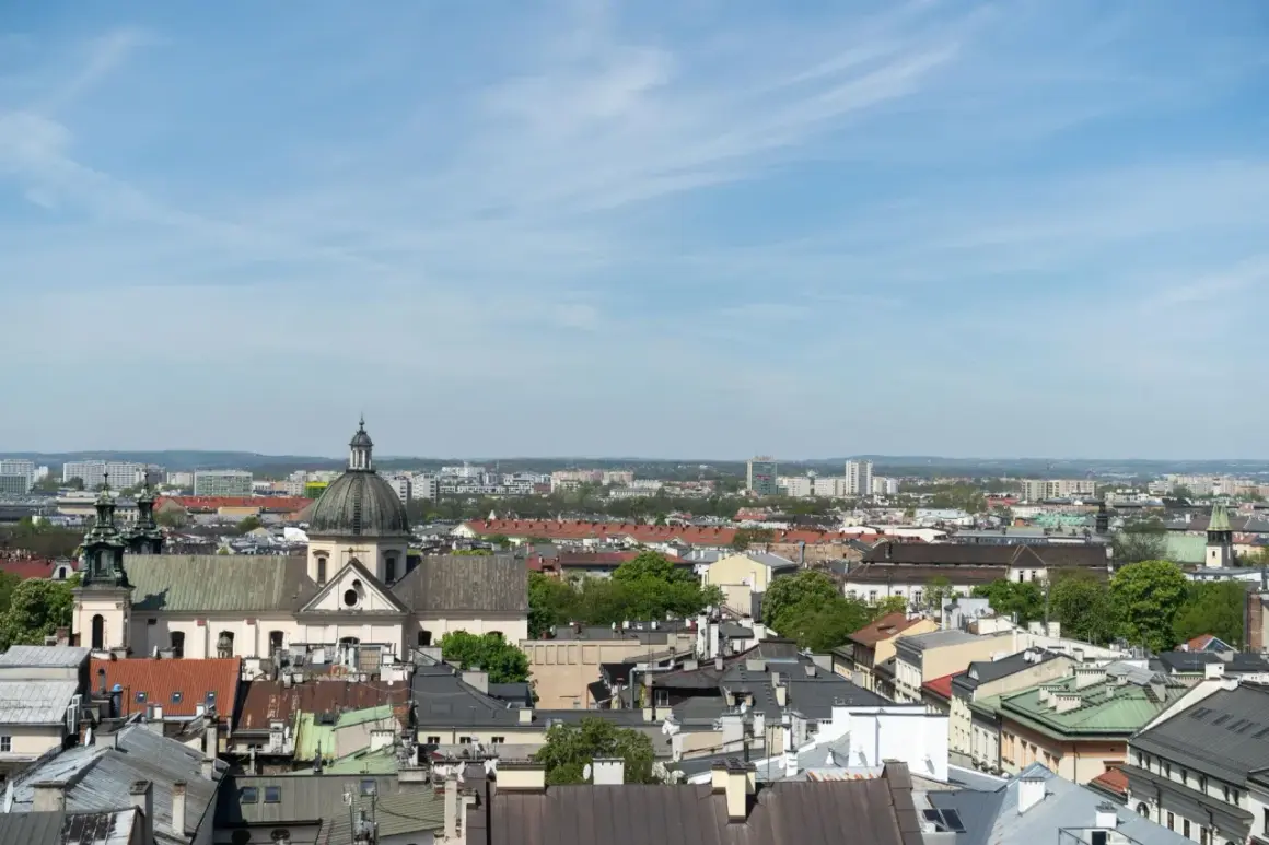 Widok na krakowskie dachy i kościół z kopułą. W tle nowoczesne budynki, które mogą wpływać na ceny mieszkań Kraków.