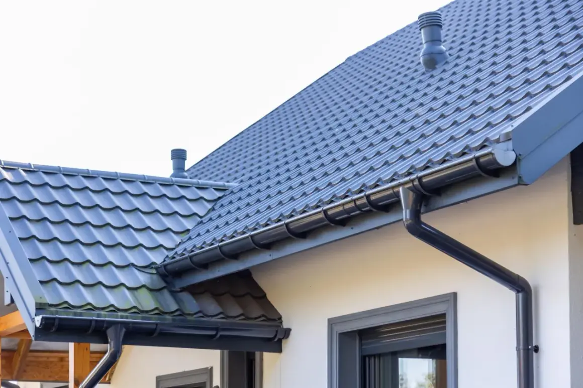 Szary dach z dachówki ceramicznej, rynny i komin. Sprawdź, jaka jest dachówka ceramiczna cena za m2 dla Twojego domu.