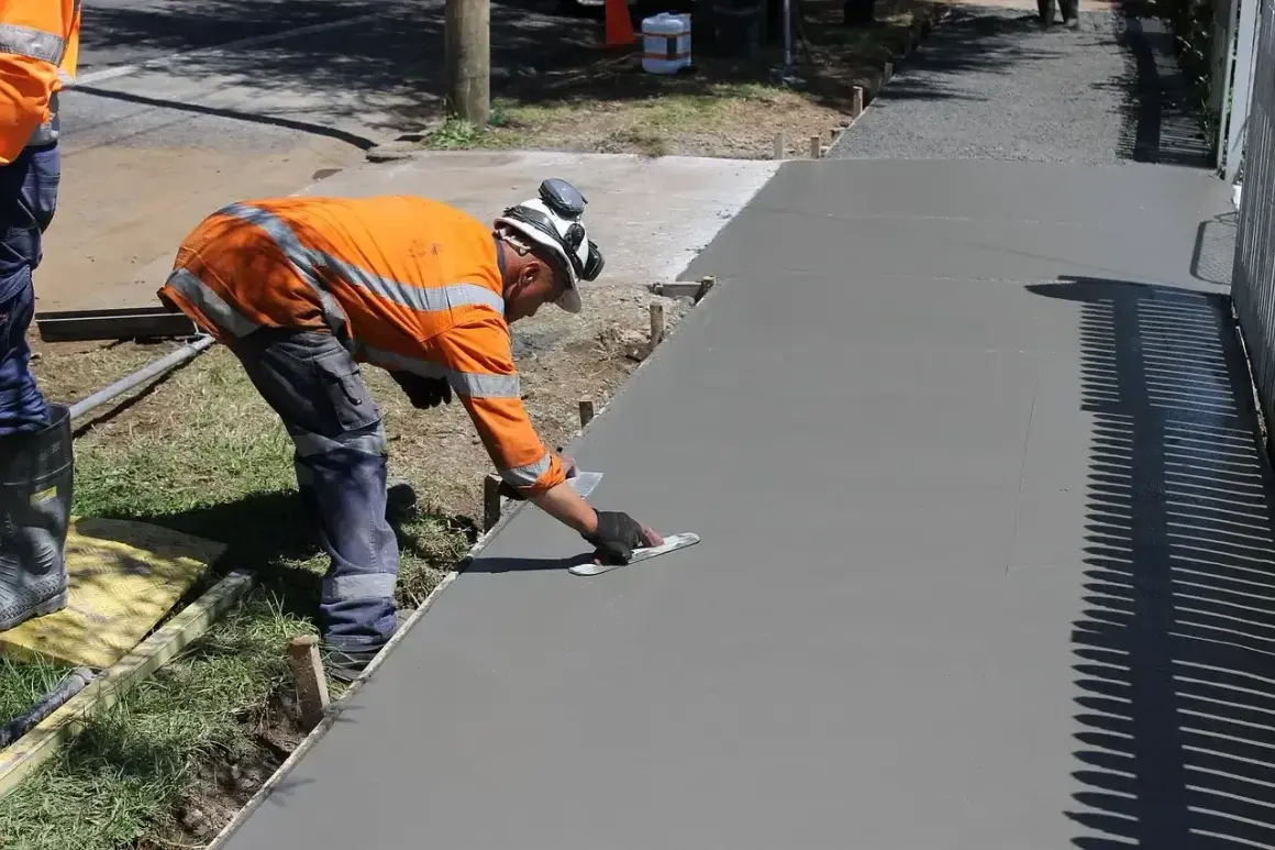 Robotnik wygładza świeży beton. Zastanawiasz się, ile kosztuje kubik betonu na podjazd?