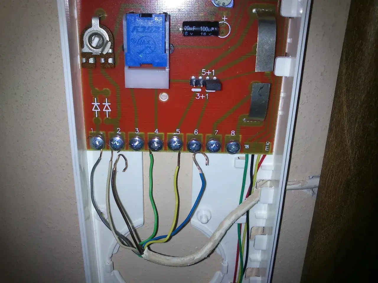 Schemat podłączenia domofonu w bloku 2 przewodowego. Widoczne zaciski śrubowe z podłączonymi przewodami, płytka drukowana z elementami elektronicznymi.