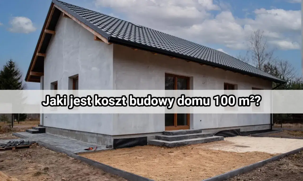 Dom w budowie, szary tynk, czarny dach. Na fasadzie napis: