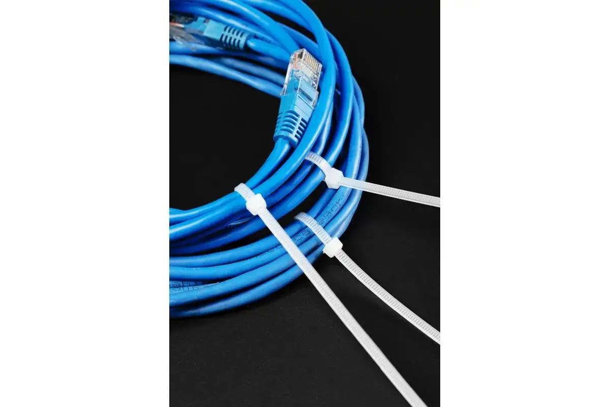 Niebieski kabel sieciowy z wtyczką RJ45, spięty białymi trytytkami. Trytytka to praktyczny sposób na uporządkowanie kabli.
