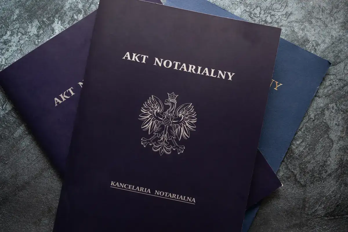 Stos dokumentów, w tym akt notarialny mieszkania, z godłem Polski.