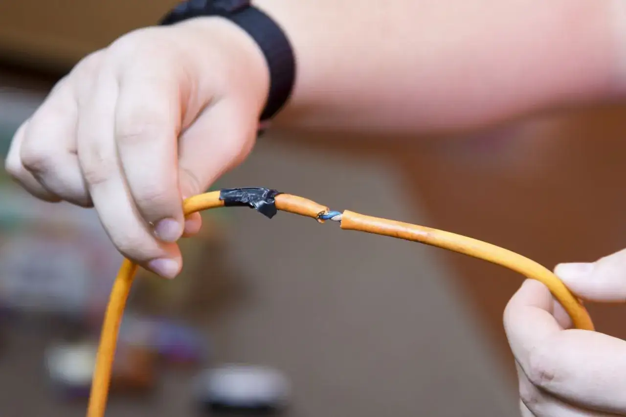 Uszkodzony kabel pomarańczowy, odsłonięte przewody. Niebezpieczne napięcie krokowe grozi porażeniem.