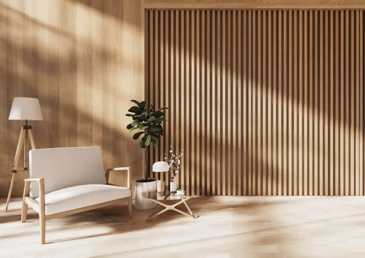 Drewniane panele podłogowe na ścianie tworzą ciepłą atmosferę. Wnętrze zdobi jasna sofa, lampa i stolik kawowy.