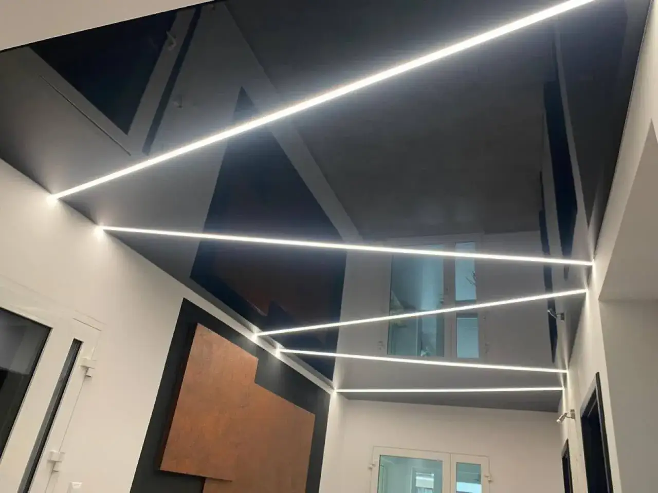 Nowoczesne sufity napinane cena: czarny, błyszczący sufit z geometrycznymi wstawkami i liniowym oświetleniem LED.