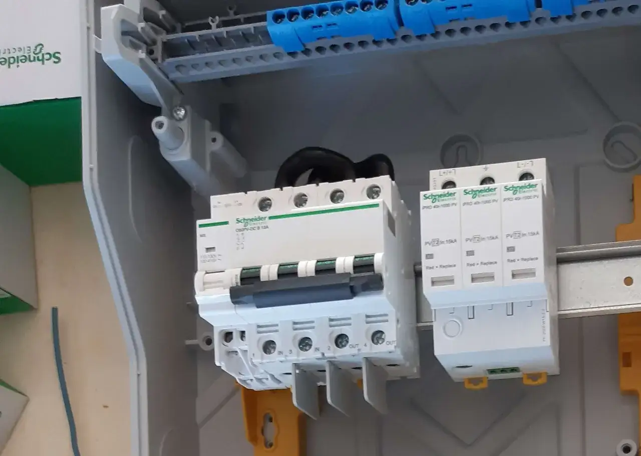 Wewnątrz skrzynki elektrycznej widoczna jest instalacja PV z wyłącznikami i zabezpieczeniami Schneider Electric.