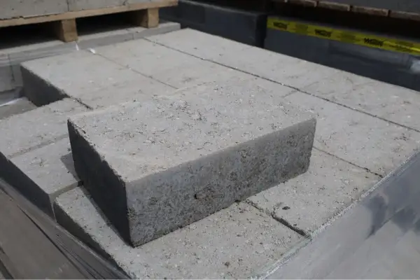 Stos szarych bloczków betonowych fundamentowych, gotowych do budowy solidnych podstaw.