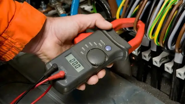 Elektryk mierzy prąd, sprawdzając potencjalny spadek napięcia w instalacji.