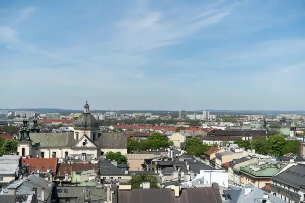 Widok na krakowskie dachy i kościół z kopułą. W tle nowoczesne budynki, które mogą wpływać na ceny mieszkań Kraków.