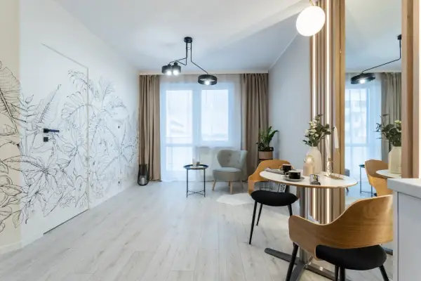 Nowoczesny salon z motywem roślinnym na ścianie. Wygodne fotele i stolik kawowy tworzą przytulną przestrzeń, idealną do relaksu. To wnętrze z rynku wtórnego zachwyca stylem.