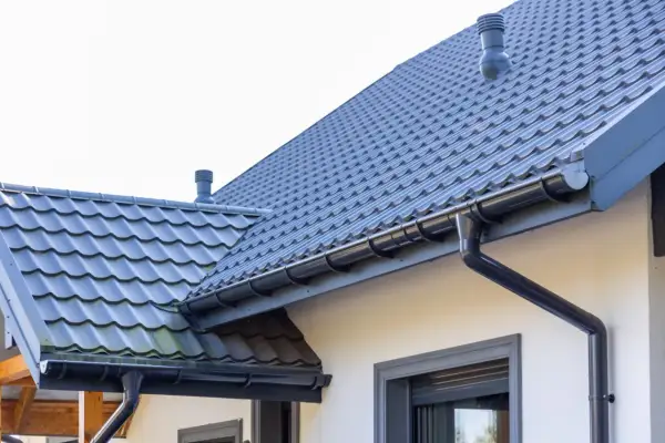 Szary dach z dachówki ceramicznej, rynny i komin. Sprawdź, jaka jest dachówka ceramiczna cena za m2 dla Twojego domu.