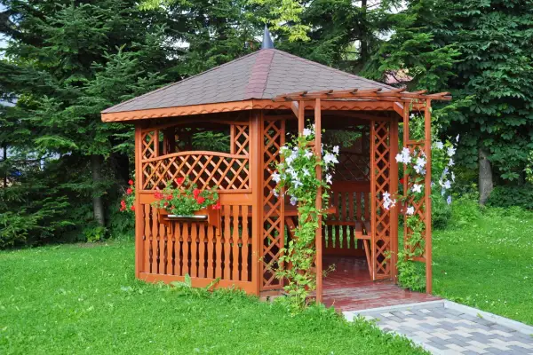 Urocza altana na działce ROD, otoczona zielenią, z kwitnącymi pnączami i pelargoniami. Idealne miejsce na relaks.