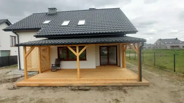 Nowy, drewniany taras w trakcie budowy, z widocznymi słupami i deskami. Idealne miejsce na letnie wieczory.