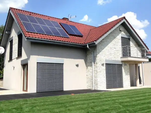 Nowoczesny dom z panelami solarnymi na dachu. Elegancka elewacja i zadbany ogród.