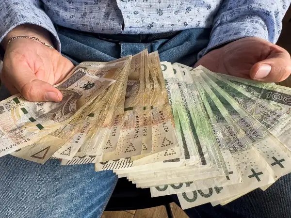 Ręce trzymające plik banknotów. To może być darowizna 200 tysięcy od rodziców, wsparcie finansowe.