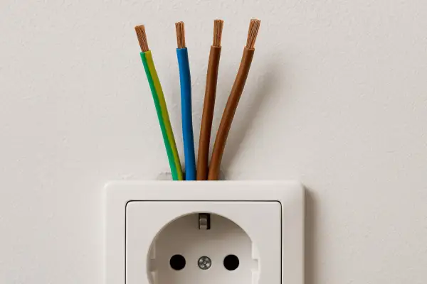 Cztery przewody wychodzące z gniazdka elektrycznego. Zastanawiasz się, jaki kabel do indukcji będzie najlepszy?