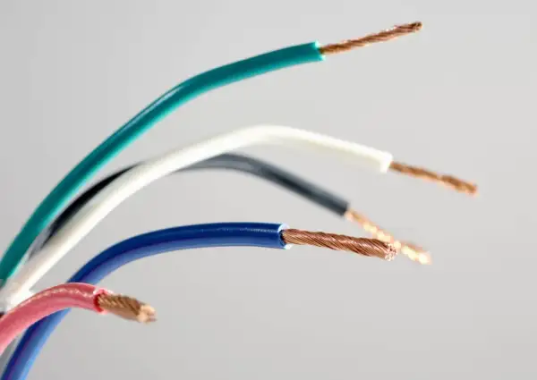 Pięć przewodów elektrycznych w różnych kolorach: zielonym, białym, czarnym, niebieskim i różowym, odsłaniających miedziane żyły. Różnorodne kolory faz.